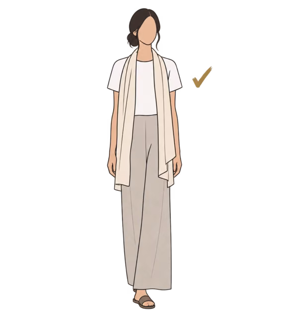 ผู้หญิงในเสื้อยืดสีขาว ผ้าพันคอสีครีมคลุมไหล่ กางเกงขายาวสีหิน และรองเท้าแตะแบบสวม มีเครื่องหมายถูกสีทอง